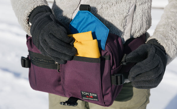 Person wearing winter gloves pulling a scarf out of the front pocket of the LPD.